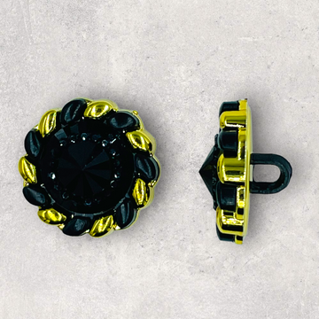 Plastknap, sort med spids kegle i centrum og guld perler i periferien, ø18mm